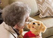 Fotografía cedida por el Departamento para Asuntos de la Tercera Edad de Florida (DOEA) donde se muestra a una anciana mientras disfruta un momento de compañía con un perro robótico de la empresa Joy for All.