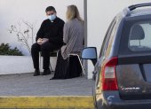 Catholic priest Jose, wearing a face mask, takes confession from a woman, as other faithful wait for their turn in their cars, outside the San Francisco de Asis church, in Santiago, on May 5, 2020. (Photo by CLAUDIO REYES / AFP)
