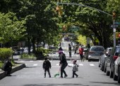 A woman plays with two children on a street, closed to vehicular traffic during a pilot program to provide more space for social distancing amid the novel coronavirus pandemic, on May 13, 2020 in Queens borough of New York City. (Photo by Johannes EISELE / AFP)