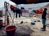 Protegidos con mascarillas, y en plena pandemia por coronavirus, habitantes del barrio pobre "Los Jazmines" extienden sus ropas recién lavadas, en el distrito de Comas, en Lima (Perú).