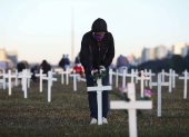 A demonstrator places flowers on a cross during a protest against Brazilian President Jair Bolsonaro and in honour of the people who died of COVID-19 in which 1000 crosses were placed in front of the National Congress in Brasilia, on June 28, 2020, amid the novel coronavirus pandemic. - The pandemic has killed at least 495,288 people worldwide, including more than 55,000 in Brazil, since it surfaced in China late last year, according to an AFP tally at 1900 GMT on Saturday, based on official sources. (Photo by Sergio LIMA / AFP)
