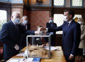 El presidente francés Emmanuel Macron (d) emite su voto en un colegio electoral en Le Touquet, Francia.