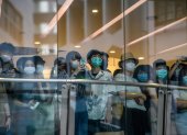 Ciudadanos con mascarilla observan a los manifestantes de una protesta contra la nueva ley de seguridad nacional para Hong Kong tras la cristalera de una tienda, el 1 de julio de 2020 en la ciudad china