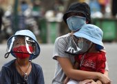 A woman waits with her children at a makeshift rapid testing centre as Vietnam records a rise in cases of the COVID-19 coronavirus in Hanoi on July 31, 2020. - Vietnam has recorded 45 news cases of COVID-19 -- its highest single daily tally since the pandemic began -- as an outbreak in the resort city of Danang erodes the country"s efforts to stay virus-free. (Photo by Nhac NGUYEN / AFP)