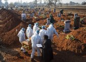 Johannesburgo. Varios miembros de familia, con trajes de protección, traslada los restos de un pariente.