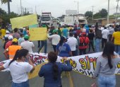 Con pancartas alusivas a sus reclamos, los funcionarios y trabajadores de los GADs bloquearon la carretera, este miércoles 13 de agosto de 2020.