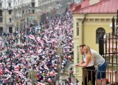 Una pareja mira a los manifestantes desde un balcón durante una marcha de partidarios de la posición.