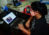 This photo taken on August 11, 2020 shows Lorraine Ann Imperio browsing her computer as she prepares to barter goods online in Las Pinas City, suburban Manila. - Struggling to make ends meet, Lorraine Imperio swapped a pair of Nike slip-ons for a whole dressed chicken on an online bartering site, one of dozens that have sprouted during the Philippines" virus lockdowns. (Photo by Maria TAN / AFP) / To go with AFP story Philippines-health-virus-lifestyle, FOCUS by Cecil Morella