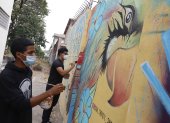Los jóvenes vecinos pintan murales que bordean el Bosque Tropical.