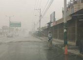 Ciudadanos en el cantón Jujan, del Guayas, esparcen agua en la calzada para evitar la dispersión de la ceniza.