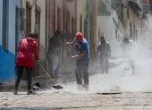 Habitantes barren la ceniza del volcán Sangay en una calle de Alausí, en la provincia de Chimborazo.
