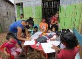 En una casa de caña, con pisos de tierra, 20 niños reciben ayuda educativa en la cooperativa Realidad de Dios. Líderes comunitarios colaboran en la tarea.
