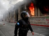 Un policía camina junto al fuego desatado, el 21 de noviembre de 2020, en el Congreso en Ciudad de Guatemala durante una jornada de protestas.