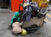 Fotografía de archivo donde se observan niños que acompañan a sus padres a trabajar con una carreta de productos vegetales en una calle de Quito.