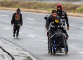 Ciudadanos venezolanos, uno de ellos con discapacidad, transitan por una carretera cercana a Quito (Ecuador).