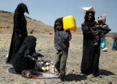 Yemeníes desplazados llevan sus raciones de alimentos proporcionadas por Mona Relief Yemen antes de una conferencia internacional de donantes sobre Yemen.