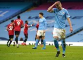 Oleksandr Zinchenko del Manchester City se lamenta, mientras al fondo celebran los jugadores del United.