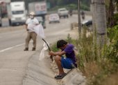Un niño ondea una bandera blanca en la carretera pidiendo ayuda por hambre.