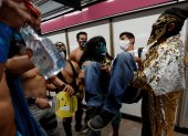 Profesionales de la lucha libre mexicana viajan concienciando del uso del tapabocas, en el metro de Ciudad de México.