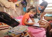 Una niña recibe clases en casa de la mano de su madre. Su hogar no cuenta con Internet.