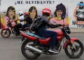 Dos motocicletas pasan frente a un mural que retrata a tres mujeres víctimas de violencia de género hoy, en Tegucigalpa (Honduras).