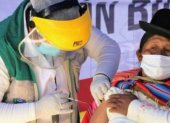 Un médico vacuna a una indígena boliviana.