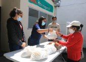 Intercambio. Alegría Parreño, Paula Herrera y Diego Yépez entregan una bolsa con alimentos a una beneficiaria de la fundación El Hormiguero.