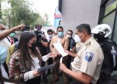 Quito. Tania Castillo pide a un policía que le permita el ingreso a la entidad. Pero las puertas fueron cerradas.