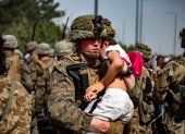 Fotografía facilitada este lunes por el Departamento de Asuntos Públicos del Comando Central de EE.UU., a través de DVIDS, en la que se registró el pasado viernes a un infante de marina estadounidense al trasladar a una niña, en la puerta del aeropuerto internacional Hamid Karzai, en Kabul (Afganistán).