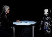 Una persona y un robot humanoide participan en un juego competitivo, mientras se mide su actividad cerebral con un electroencefalograma.