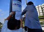 Momento en que el personal del Municipio de Guayaquil pega la sanción en el poste de una valla publicitaria.
