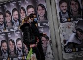 Una pareja camina frente a un cartel con la cara de Leandro Santoro, candidato a Diputado Nacional por el Frente de Todos, el 9 de septiembre de 2021, en la Ciudad de Buenos Aires (Argentina). Argentina volverá a las urnas este domingo para elegir en unas primarias abiertas a los candidatos que competirán en los comicios legislativos de noviembre próximo, un proceso electoral marcado por la pandemia de la covid-19. Unos 34,3 millones de argentinos están convocados para definir con su voto las listas de candidatos que quedarán habilitadas para competir en los comicios del 14 de noviembre, en los que se renovarán 127 de los 257 escaños de la Cámara de Diputados y 24 de las 72 bancas del Senado.