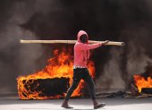 Un hombre camina junto a un neumático gigante en llamas durante una jornada de protestas en Haití, en una fotografía de archivo.