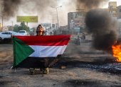 Un manifestante sudanés sostiene la bandera nacional junto a neumáticos en llamas durante una manifestación en la capital, Jartum, Sudán, el 26 de octubre de 2021.