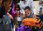 Un niño reacciona luego de abrir un regalo de "Un Juguete, una buena noticia" , en Caracas (Venezuela). EFE/ RAYNER PEÑA R.