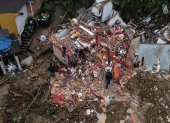Fotografía tomada con un drone que muestra a dos hombres junto a una vivienda destrozada en medio de la destrucción tras las fuertes lluvias del martes en el Morro de la Oficina, el 18 de febrero de 2022, en la ciudad de Petrópolis, estado de Rio de Janeiro (Brasil).