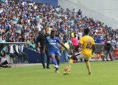 Romario Caicedo, jugador de Emelec, domina el balón mientras Ismael Rescalvo, entrenador azul, sigue la acción.