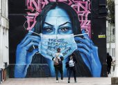 Un mural en Bogotá, donde una mujer sostiene una mascarilla, hace referencia a la terrible pandemia de la COVID-19 en el mundo.