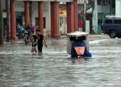 Varias personas caminan por una calle llena de agua, hoy en La Habana (Cuba).