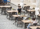 Imagen de archivo de una trabajadora recoge una mesa de una terraza en un bar.