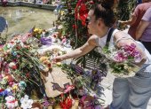 Fotografía de archivo, tomada el pasado 29 de mayo, en la que se registró a una mujer al hacer una ofrenda floral frente a la institución académica Robb Elementary School, en Uvalde (Texas, EE.UU.), luego de que un joven desadaptado asesinara a 19 niños y dos maestras e hiriera a otras 17 personas.