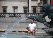 Un hombre descansa bajo una fuente en Trafalgar Square, en Londres. EFE/EPA/NEIL HALL