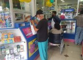 Segundo Luna, de 70 años, retira su insulina en la farmacia ubicada frente al Hospital Abel Gilbert, en el suroeste de la ciudad. Al fondo, un familiar hace lo mismo con los fármacos de un persona con movilidad reducida.