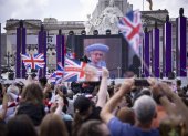 Londres. Gente en el centro comercial viendo a Su Majestad, la Reina en el balcón del Palacio de Buckingham mostrado en una pantalla grande durante las celebraciones del Jubileo de Platino de la Reina Isabel II, el 2 de junio de 2022.