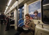Una mujer viaja en el metro sentada frente a un cartel en el que se muestra a un soldado ruso, este martes en Moscú (Rusia).