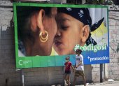 Un hombre y su hija pasan caminando frente a una valla que hace parte de la campaña por el SÍ en el referendo sobre el código de familia, hoy en La Habana (CUBA).