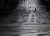 Fotografía de archivo de un transeúnte que cruza una calle completamente vacía en Sídney, Australia.