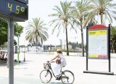 Sevilla. Una mujer en bicicleta pasa junto a un termómetro que marca 45 grados en una calle de esta urbe.