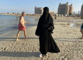 Una joven árabe camina con su indumentaria habitual por la playa. Para tomarle una foto se debió pedir permiso, son las normas.