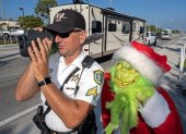 El  coronel de la oficina del alguacil del condado de Monroe, Lou Caputo, disfrazado de Grinch, y al diputado Andrew Leird mientras miden la velocidad de conductores en la autopista Florida Keys Overseas, en Marathon (Florida, EE.UU.). EFE/Andy Newman